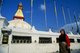 Nepal: Tibetan woman below the all seeing eyes of the great dome of Bodhnath stupa, Kathmandu